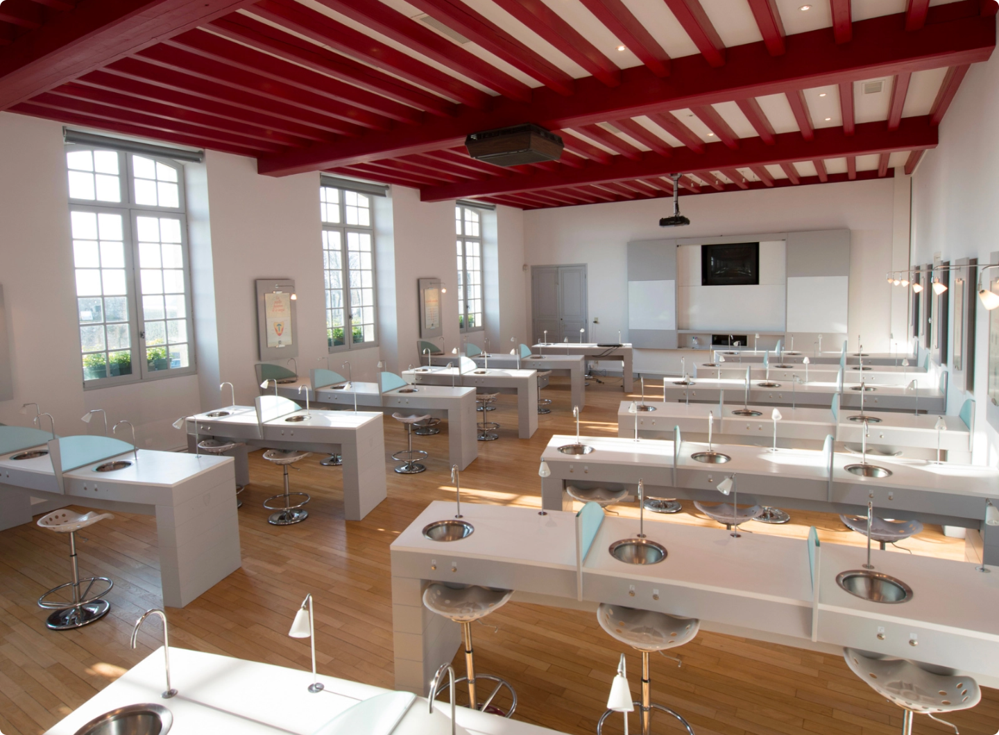 Salle de cours de l'École du Vin de Saint-Émilion avec postes de dégustation professionnels et table des arômes au fond